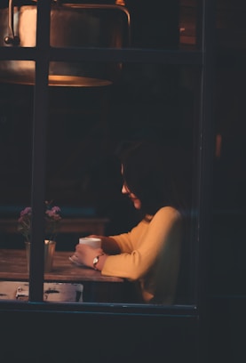 woman sitting beside table holding cup