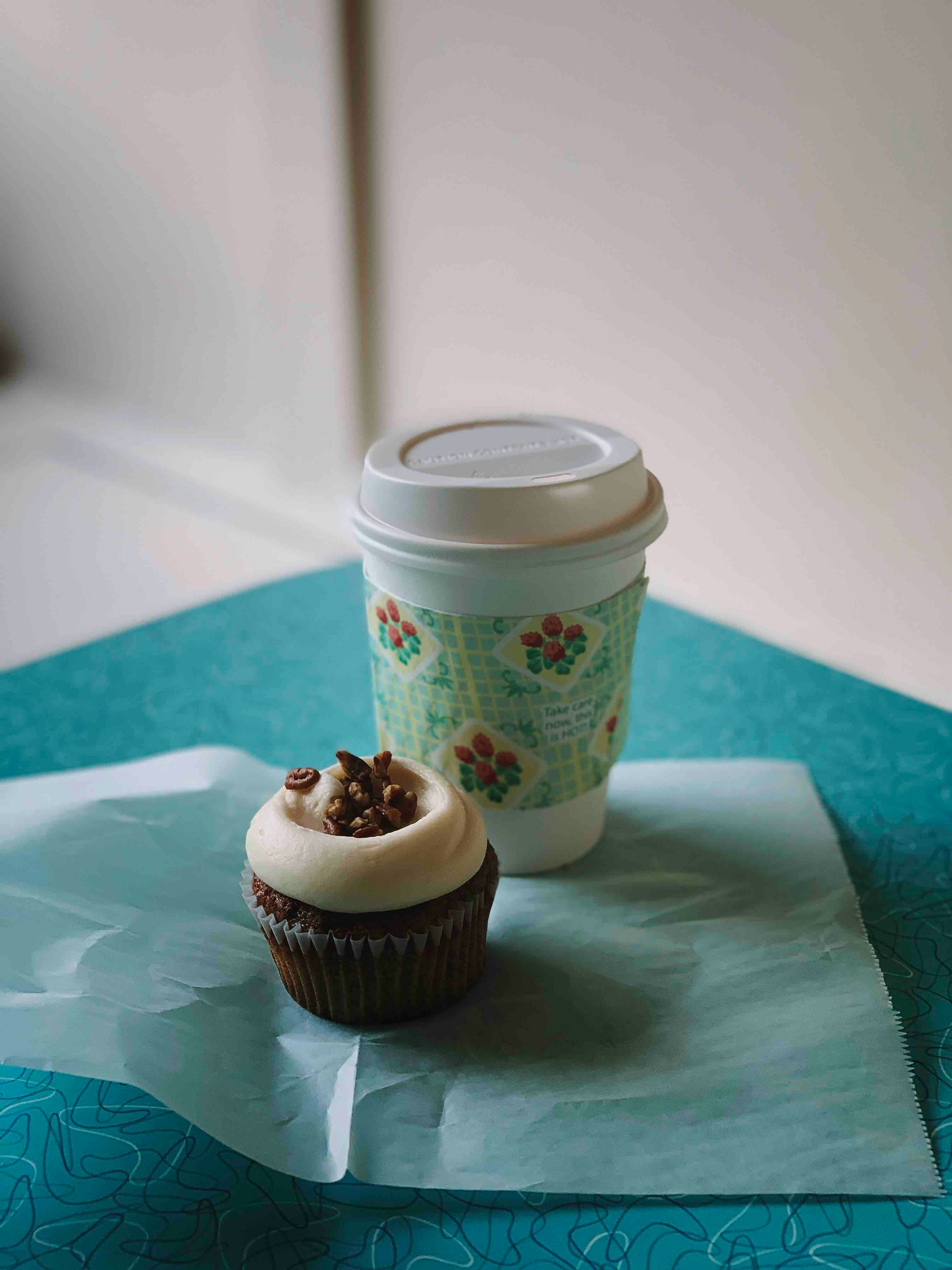 white and blue disposable cup beside chocolate cupcake
