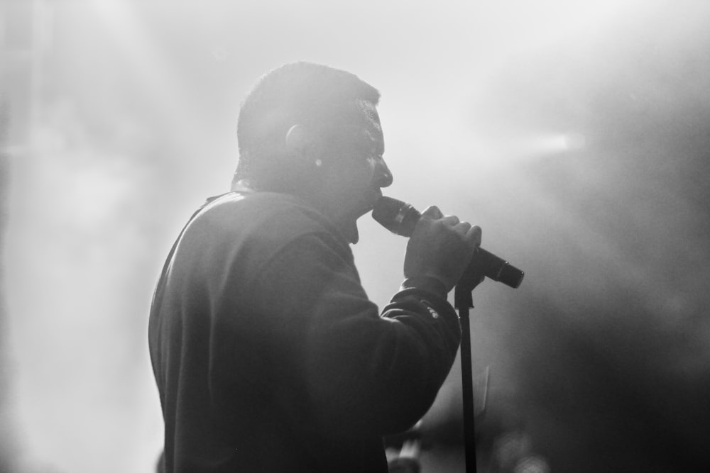grayscale photo of man using microphone