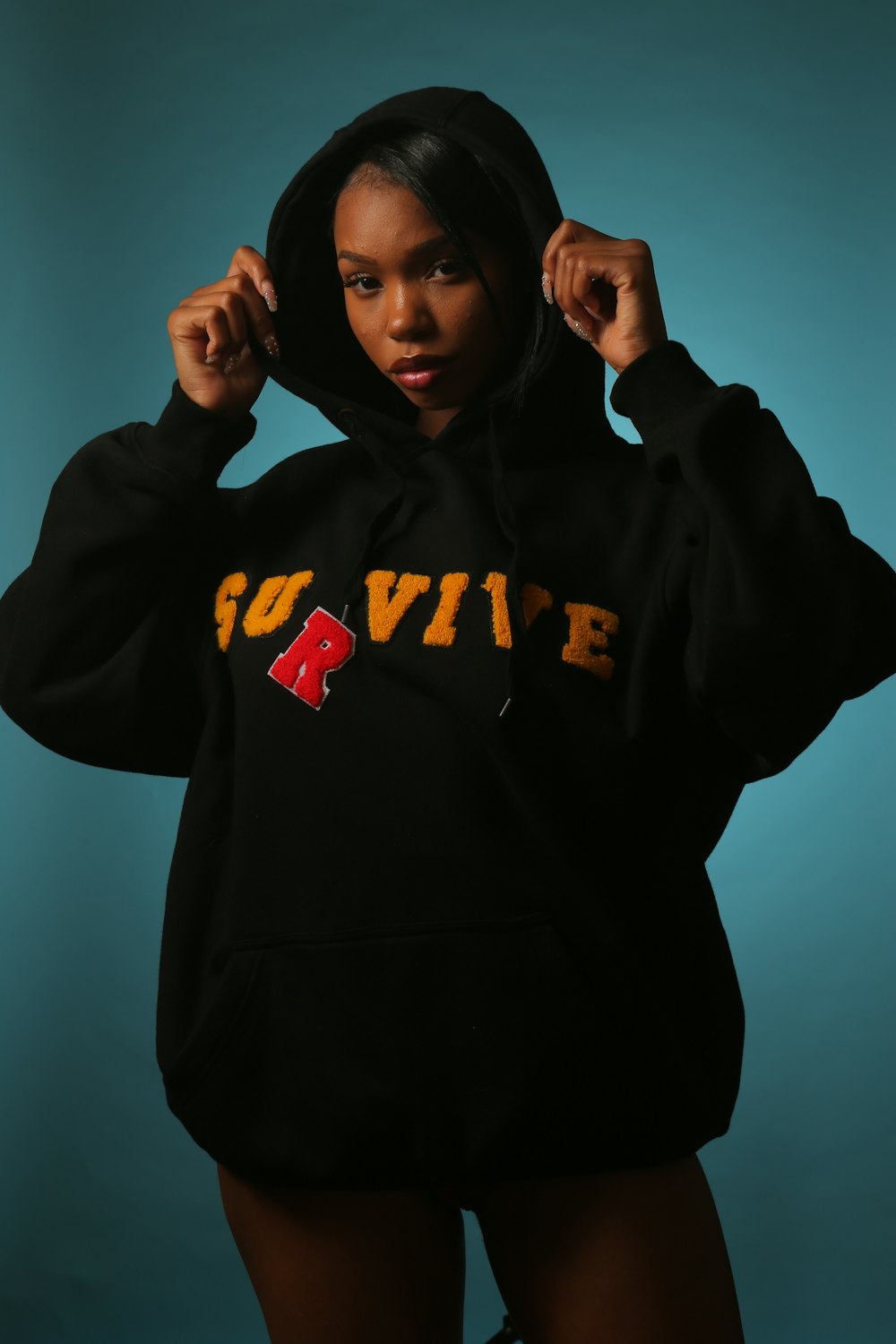 woman wearing black and yellow hooded jacket standing and touching edge of her jacket