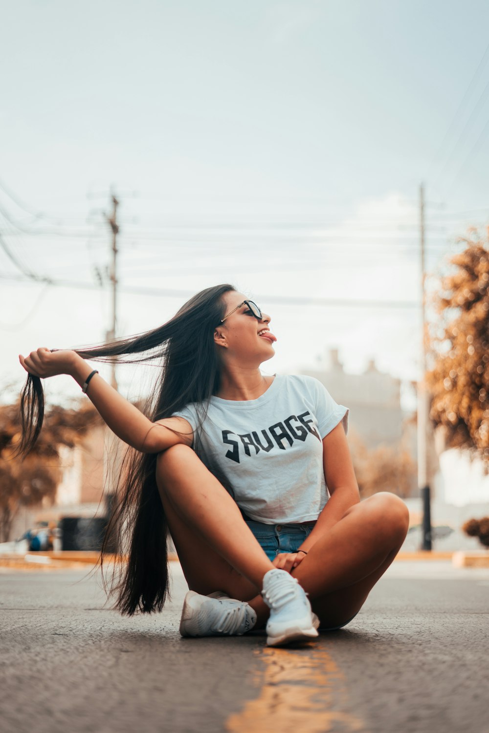 woman sitting on road wearing white shirt during daytime