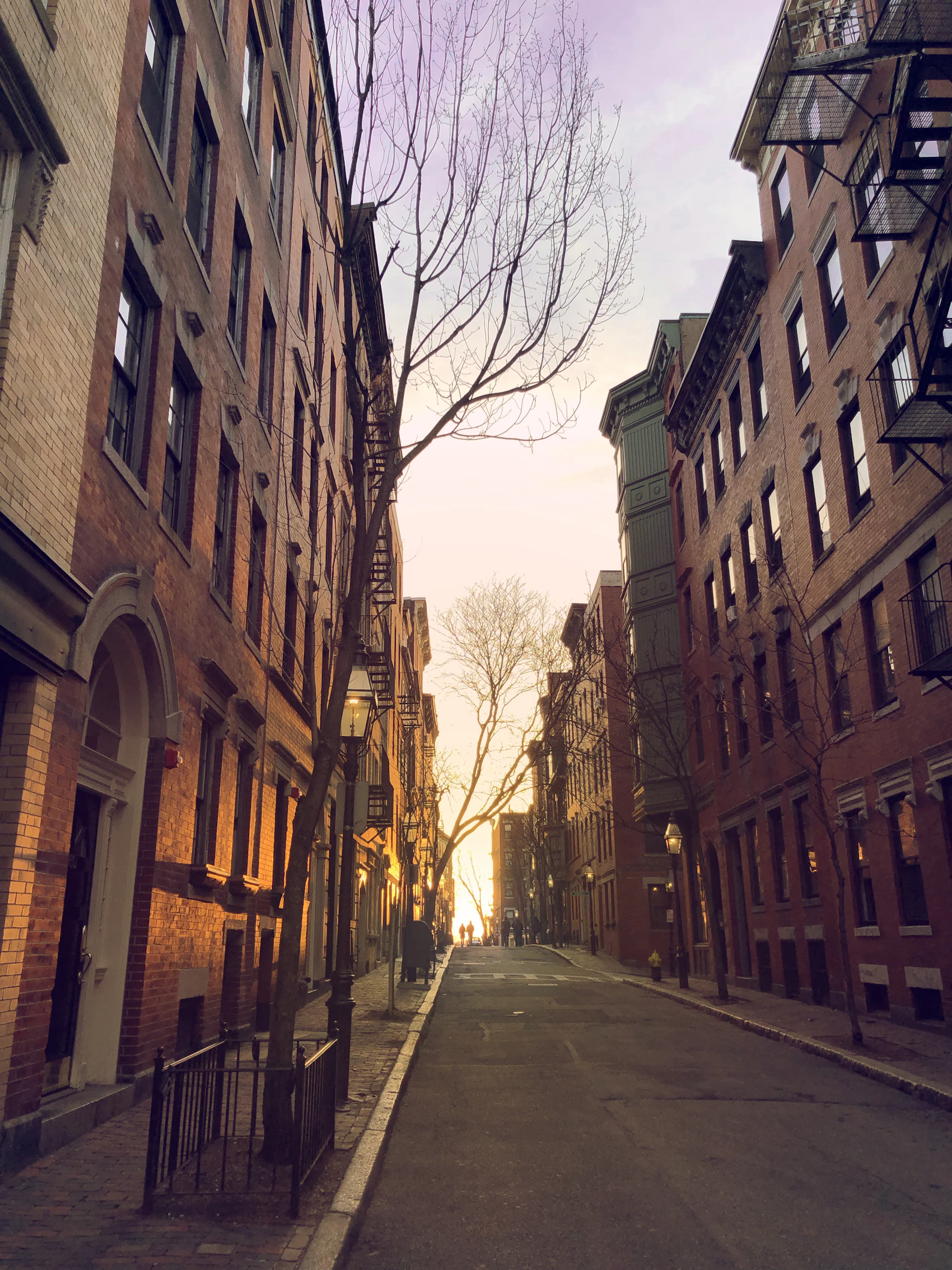 Historic Beacon Hill streets and the Boston skyline in warm evening light