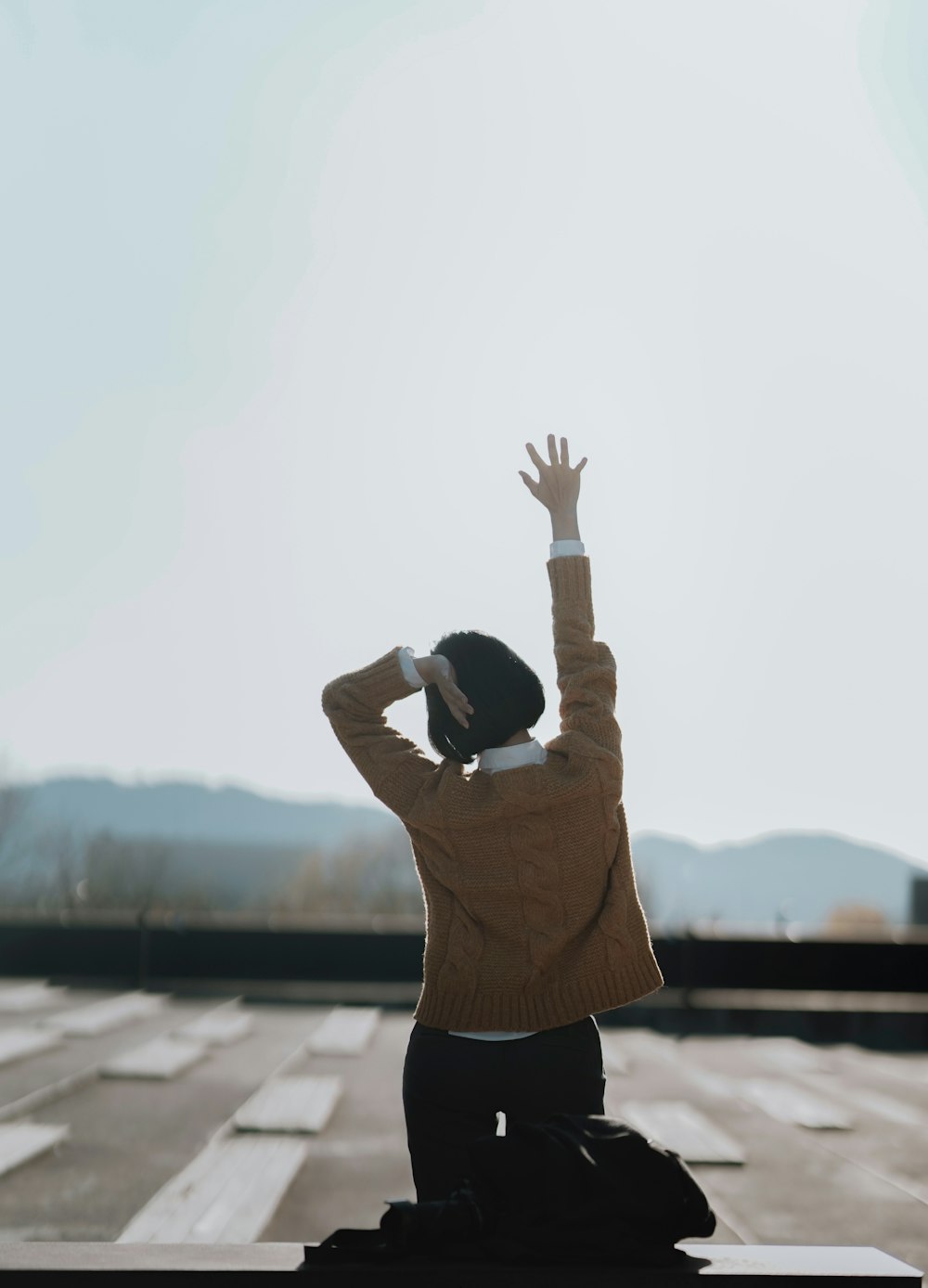 woman wearing brown jacket right hand raising during daytime