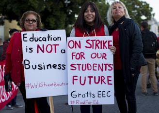 three women holding signges