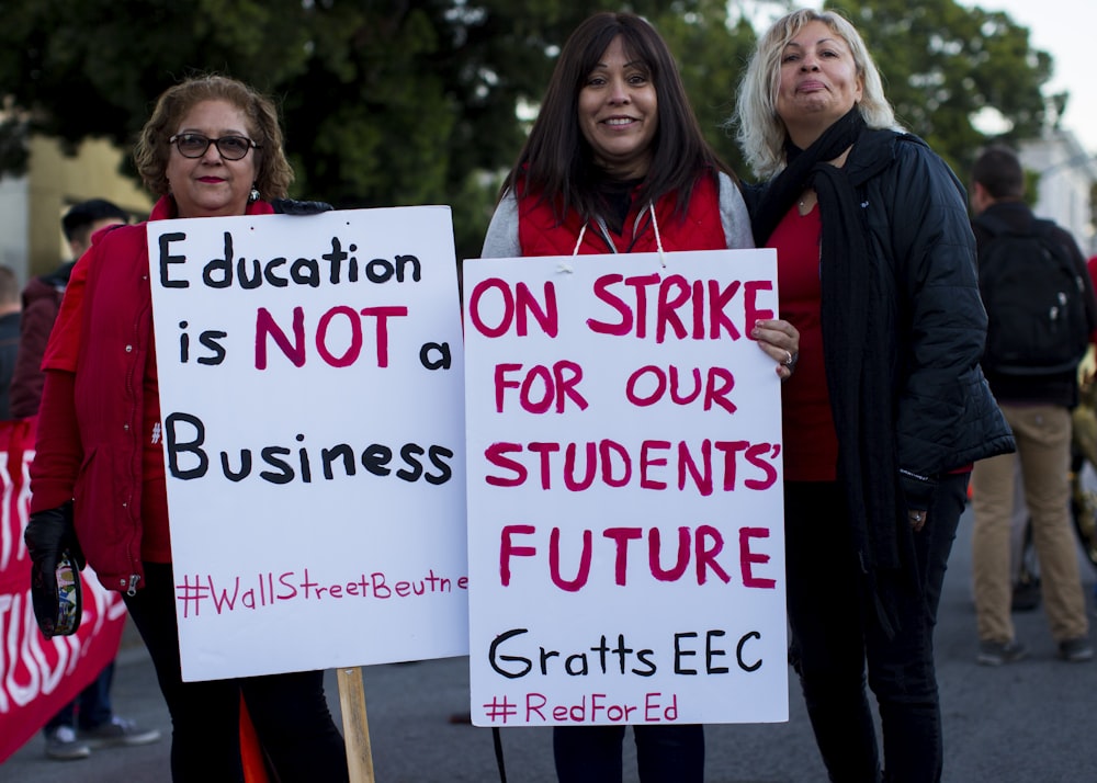 three women holding signges