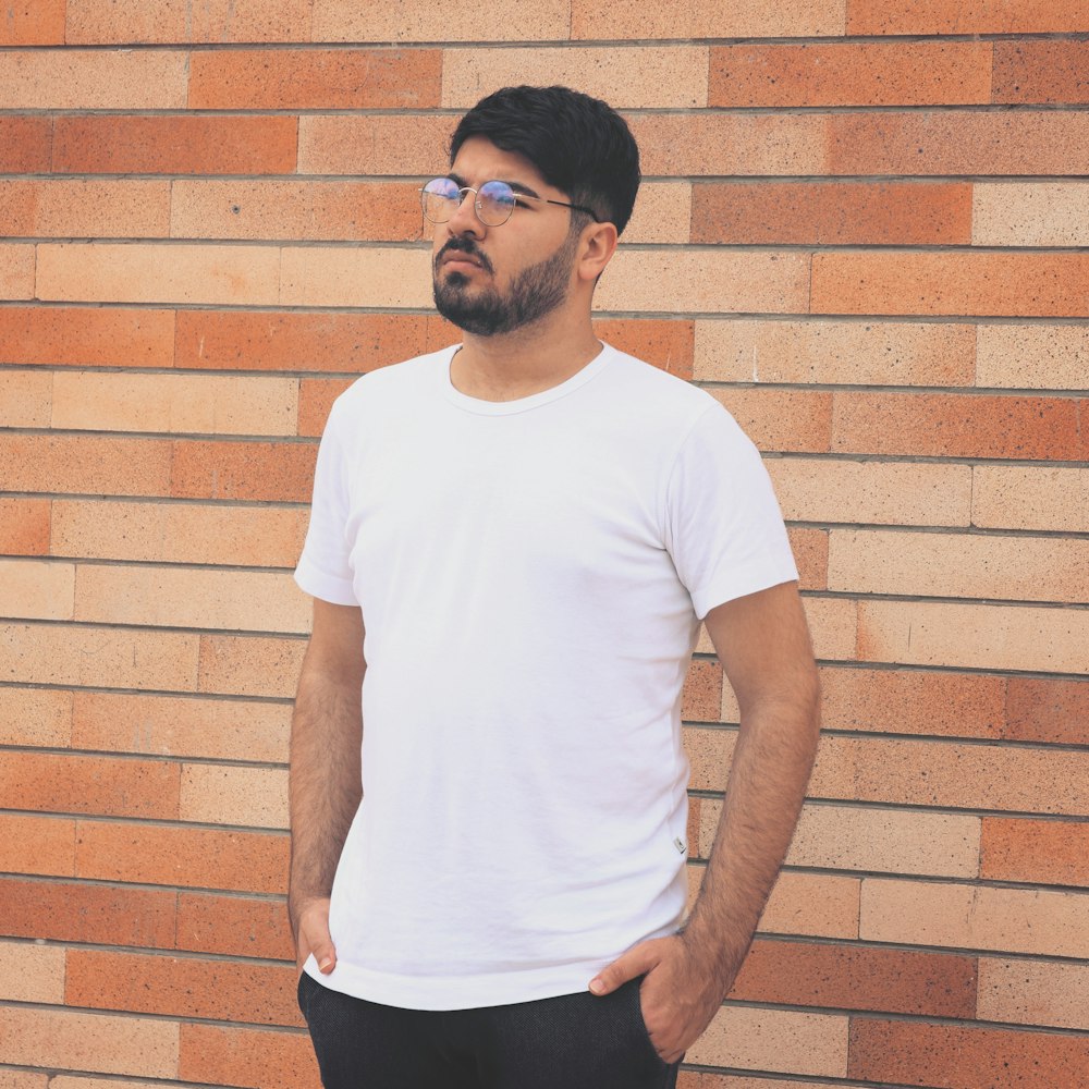 man standing beside brick wall