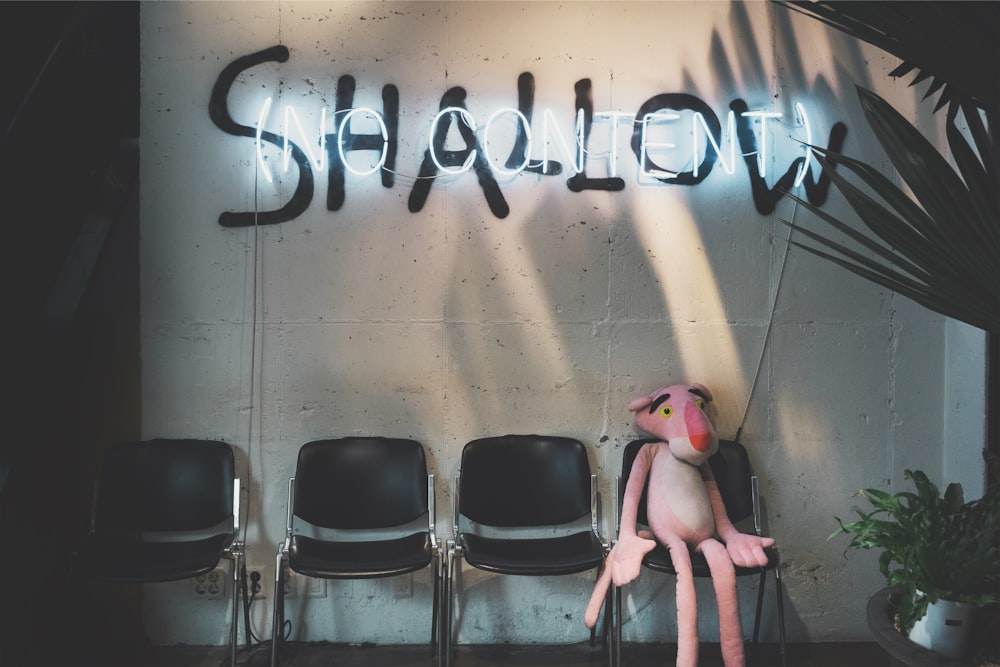 Pink Panther plush toy sitting under shallow sign