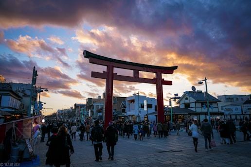 A vibrant torii gate glowing under a sunset sky in Japan.
