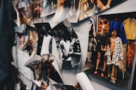 A collection of photographs is displayed on a wall, including both black and white and color images. One image shows a group of people in stylish and bold clothing, while another displays an individual in a casual pose. The arrangement appears informal, with some photos curling at the edges.