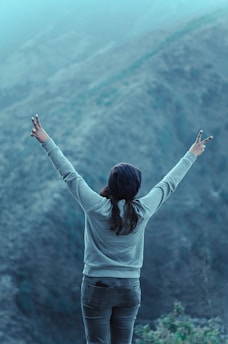 woman raising both hands and doing peace sign