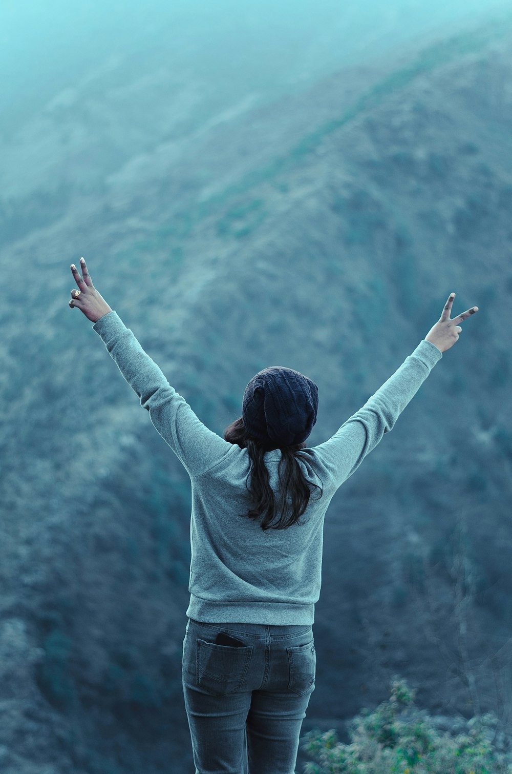 woman raising both hands and doing peace sign