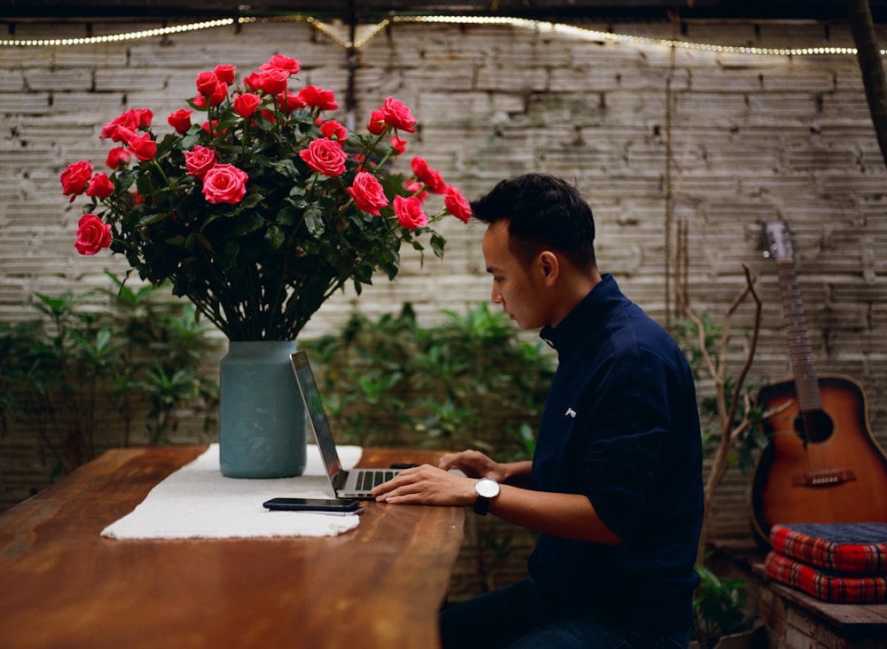 man sitting on chair using laptop