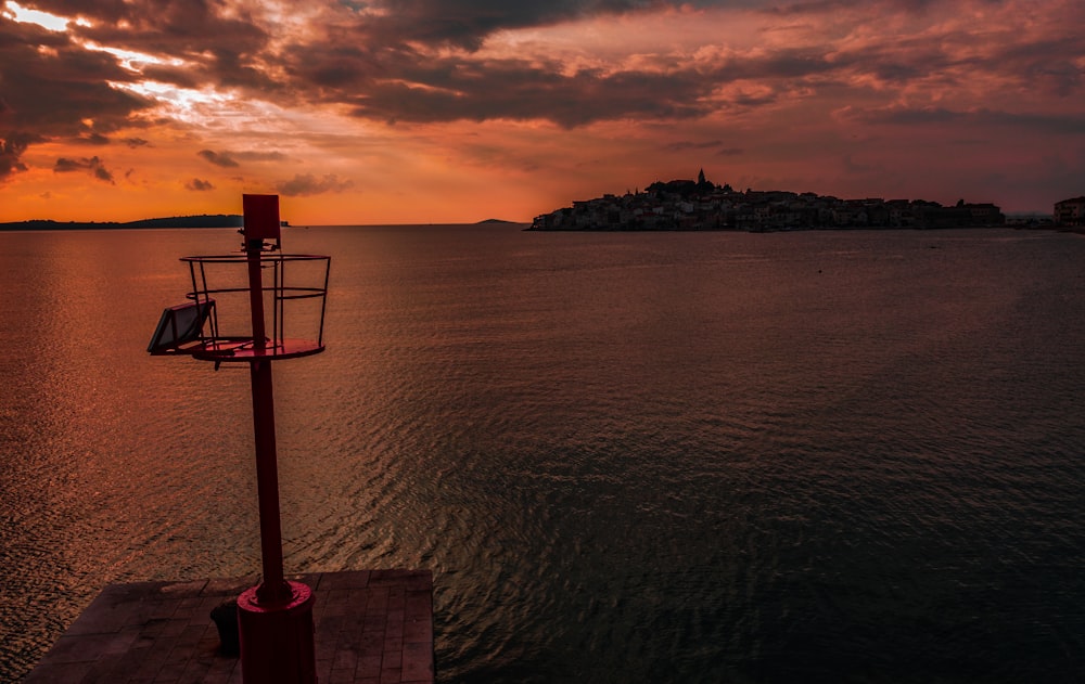 silhouette photography of tower near body of water