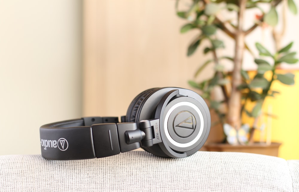 shallow focus photo of black wireless headphones on gray textile