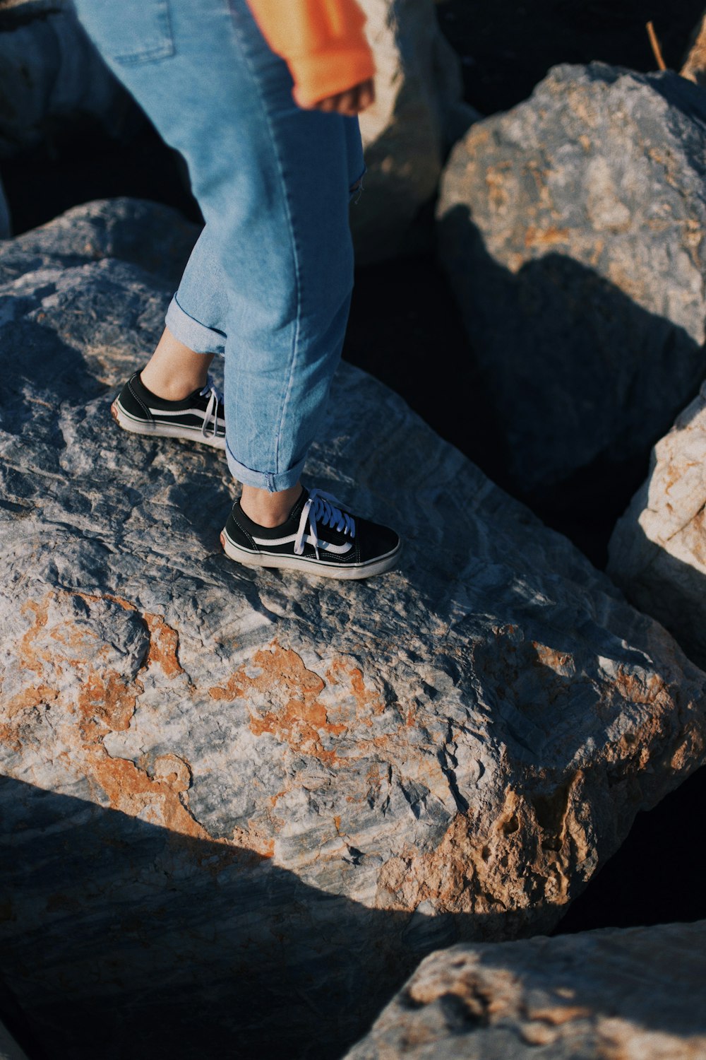 person wearing blue denim jeans standing on rck