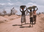 three women carrying basin while walking barefoot