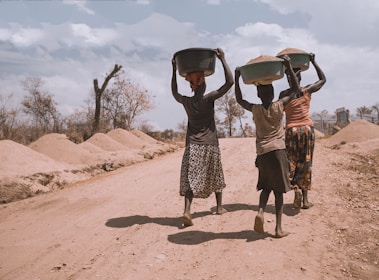 three women carrying basin while walking barefoot