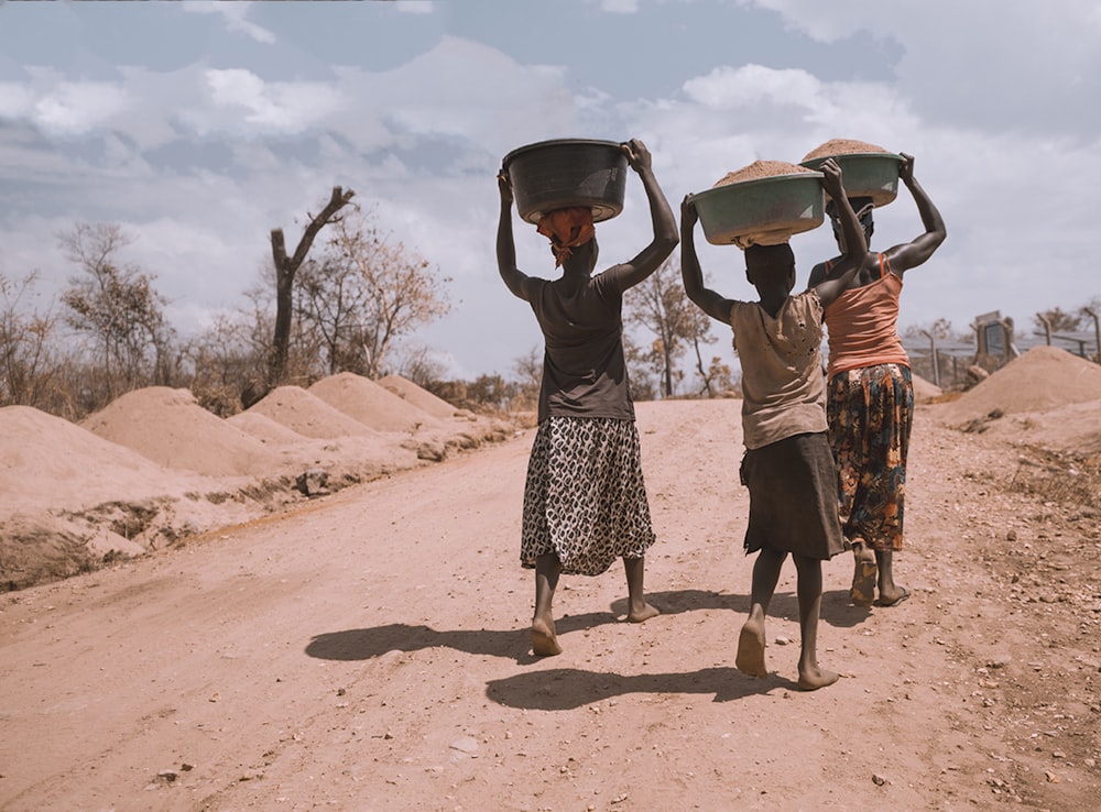 Tres mujeres cargando una palangana mientras caminan descalzas