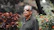 Happy retired man enjoying a sunny day outdoors with tropical plants.