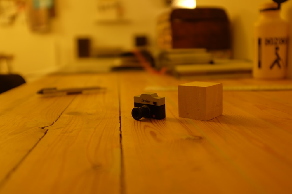 black and gray camera and brown wooden cube