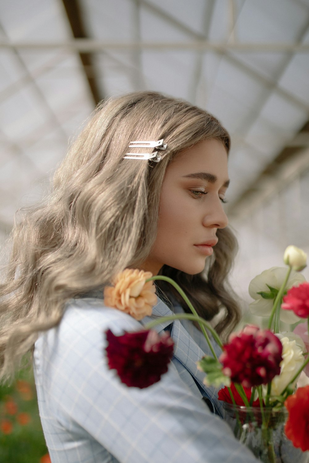 woman wearing grey shirt carrying flowers inside greenhouse