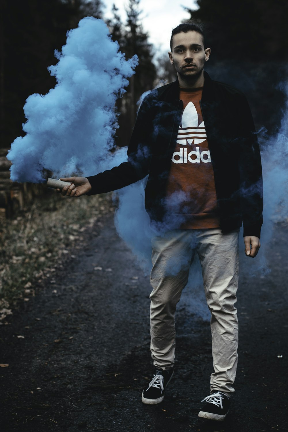 man wearing jacket holding blue smoke