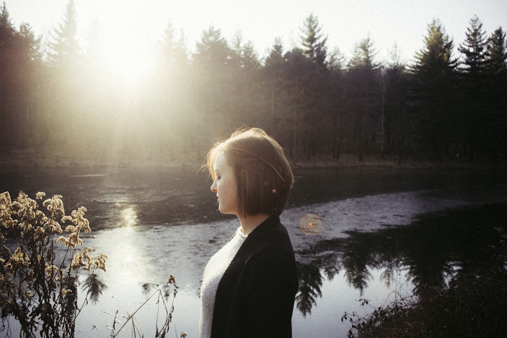 woman looking at flowers near body of water