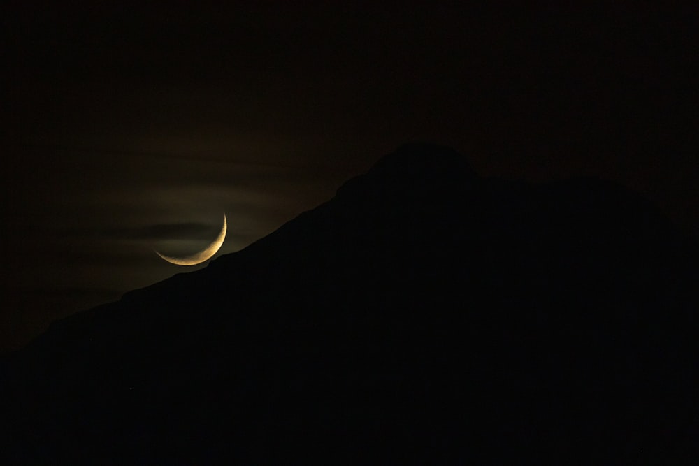 silhouette of mountain with crescent moon