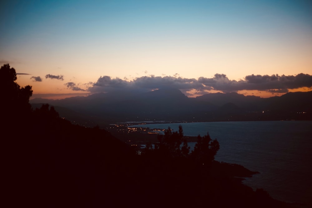 silhouette photography of mountain near body of water