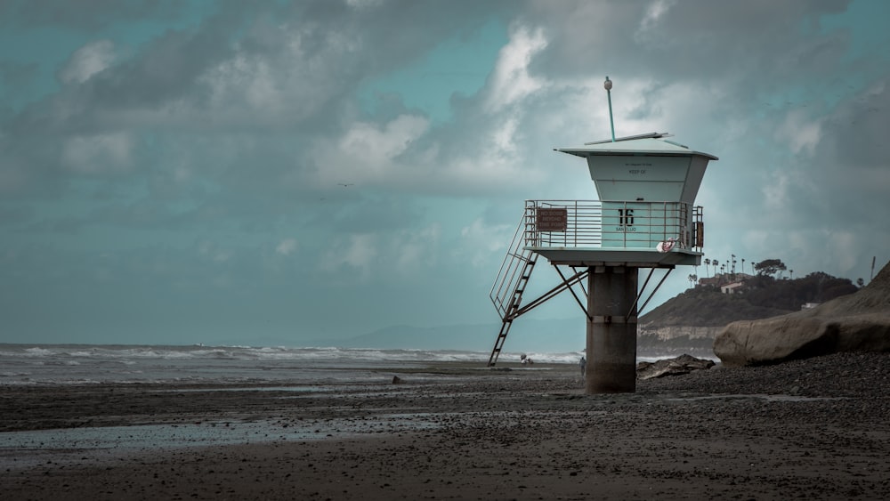 white and gray concrete lifeguard house under cloudy sky during daytime