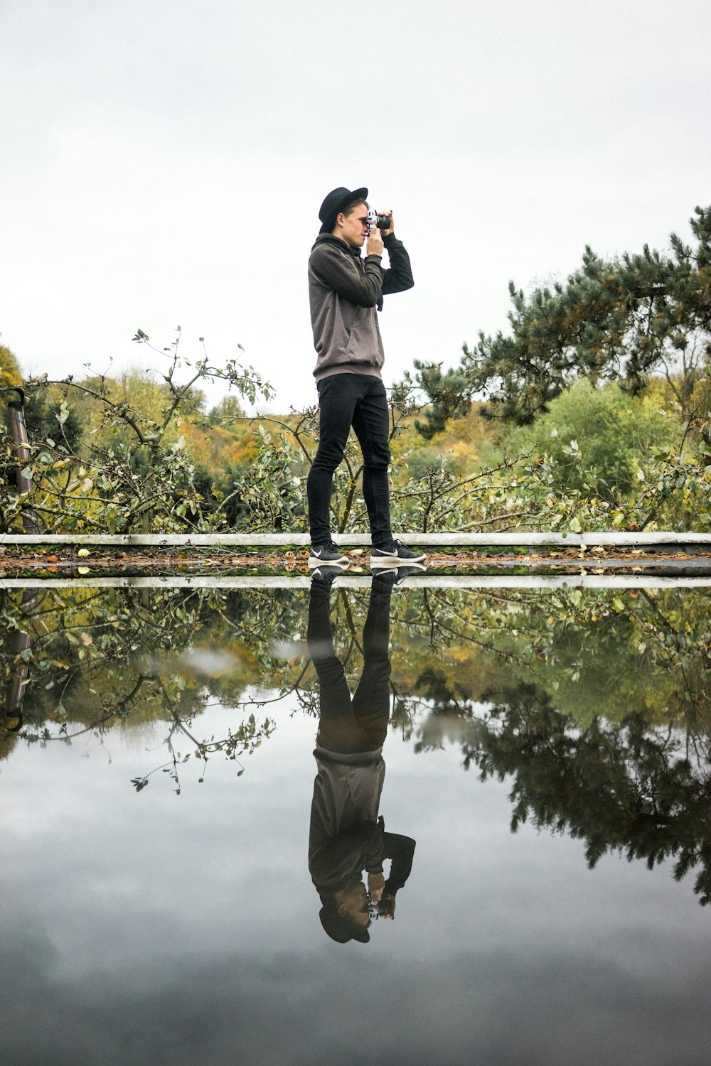 man standing near body of water using camera