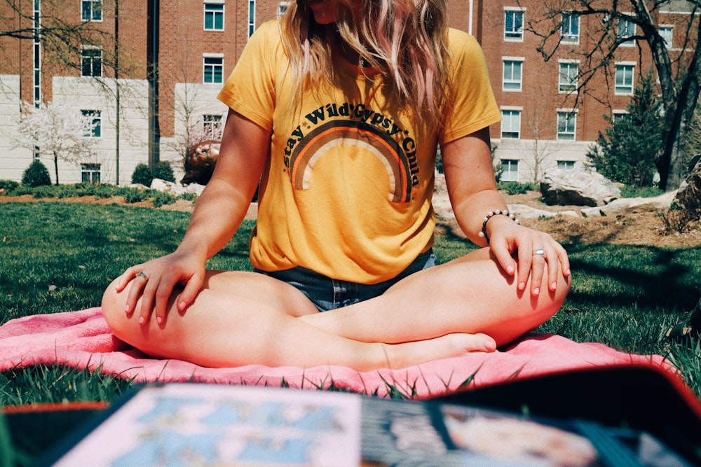 femme assise en jambes croisées sur le champ d’herbe avec couverture