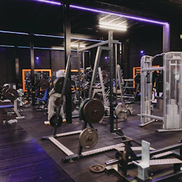 Modern gym equipment glowing softly with neon green highlights in a dark room.
