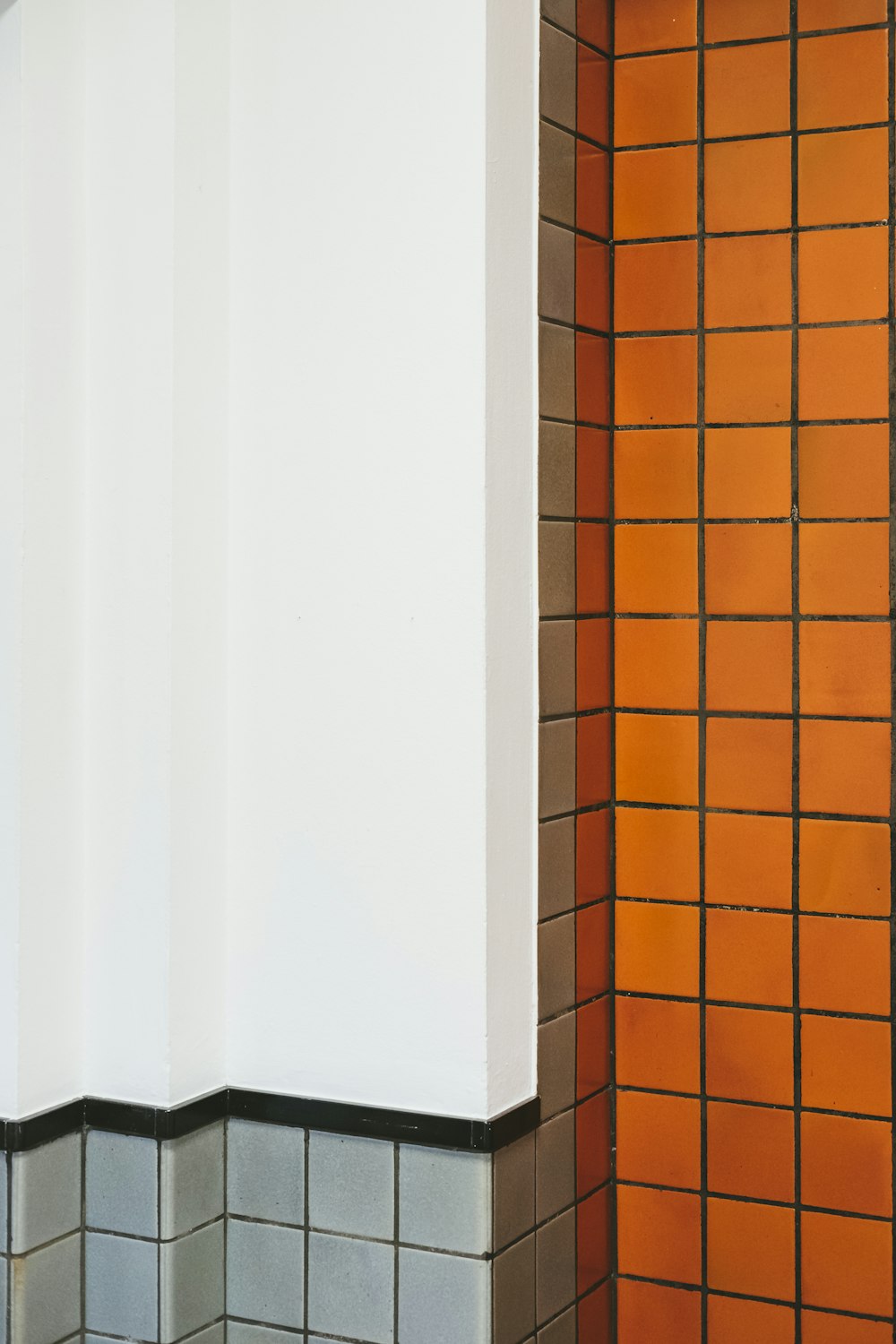 a bathroom with orange and gray tiles and a white toilet