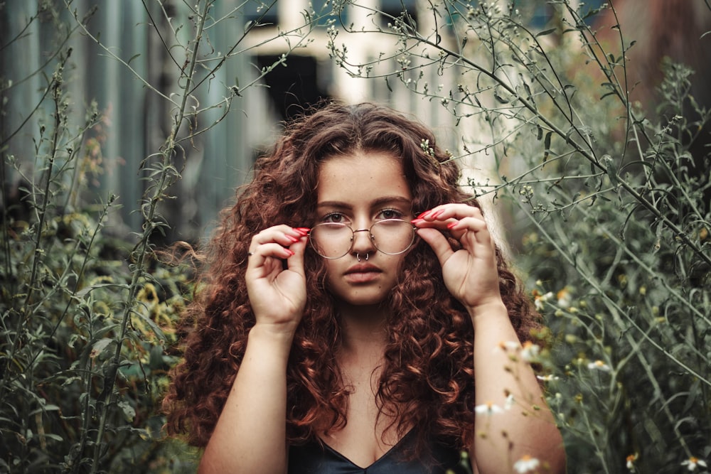 selective focus photography of woman holding her eyeglasses during daytime