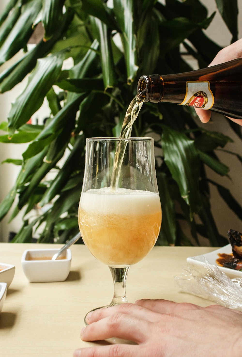 person pouring beer in clear wine glass