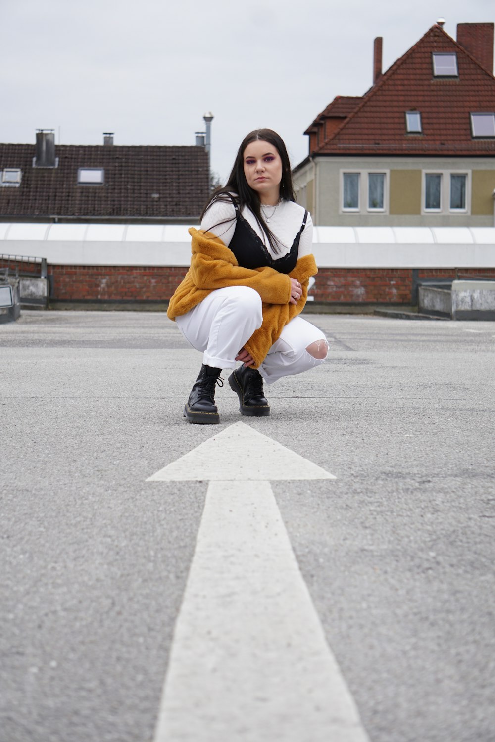 woman in white pants front of arrow paint on road