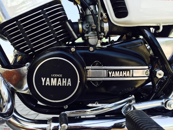 A close-up image of a motorcycle engine featuring the Yamaha branding prominently displayed on the engine casing. The engine has a combination of black and chrome elements, with visible components such as fins, bolts, and a foot peg. The overall appearance is clean and well-maintained, highlighting details of the engine's structure.