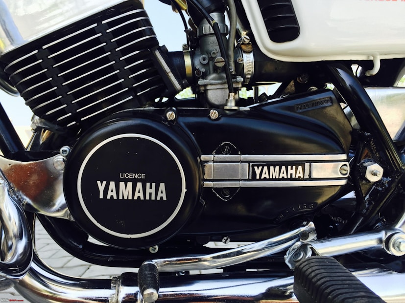 A close-up image of a motorcycle engine featuring the Yamaha branding prominently displayed on the engine casing. The engine has a combination of black and chrome elements, with visible components such as fins, bolts, and a foot peg. The overall appearance is clean and well-maintained, highlighting details of the engine's structure.