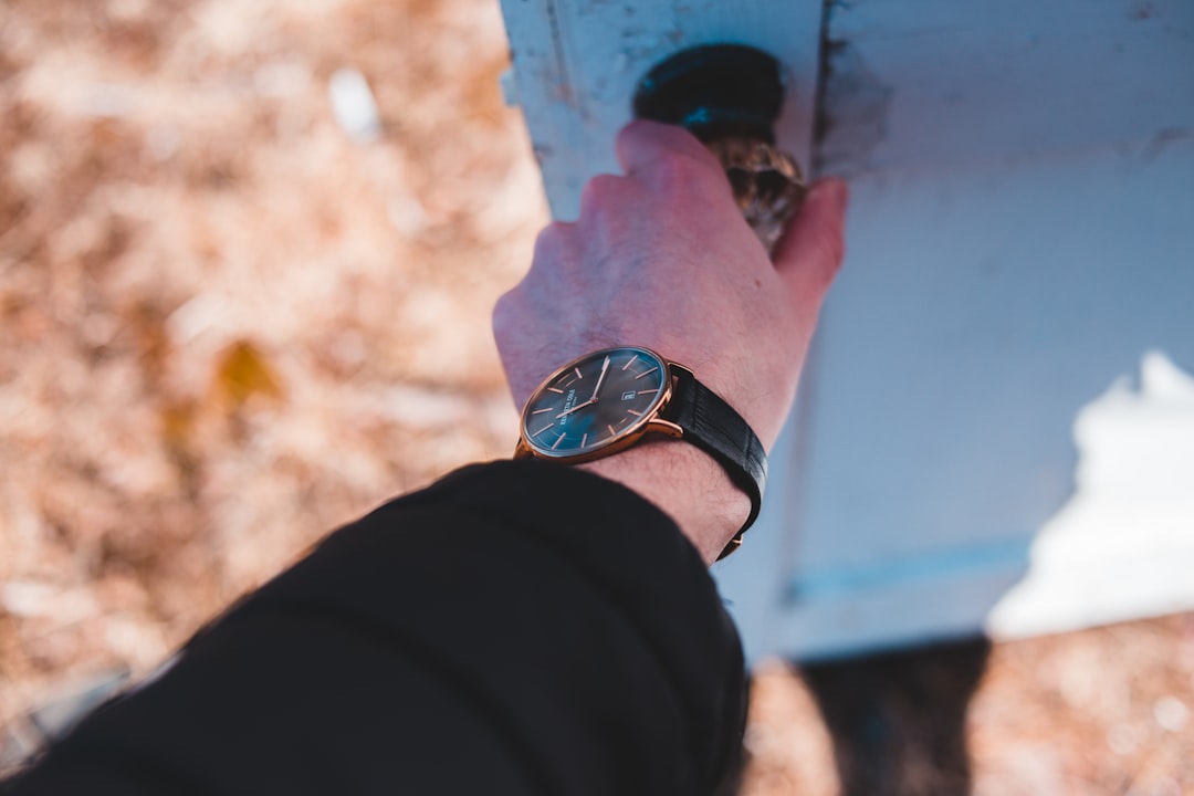 round gold-colored analog watch with black leather band