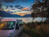 A cozy campervan parked by a serene lakeside at sunset.