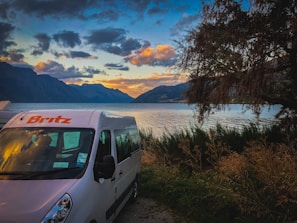 A scenic view of the skoolie by a lakeside campsite.