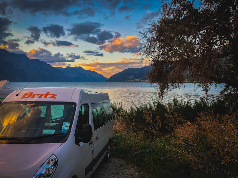 A cozy camping trailer parked by a serene lake at sunset in Mexico