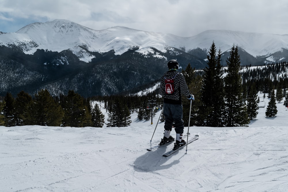 man skiing facing maountains and trees