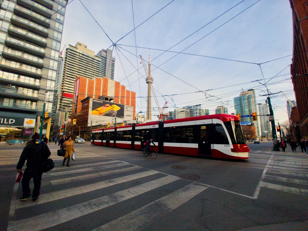 personnes marchant sur une voie piétonne à côté d’un train rouge et blanc