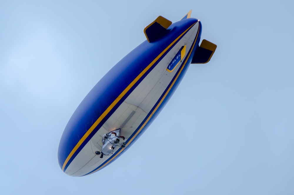 Blau-weißes Luftschiff fliegt unter blauem Himmel