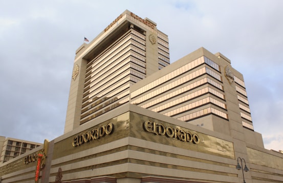 A large modern hotel or casino building with multiple stories is prominently displayed. The structure is adorned with gold-toned accents and large reflective windows. The name 'Eldorado' is visible on the building facade, with architectural features including geometric lines and decorative emblems.