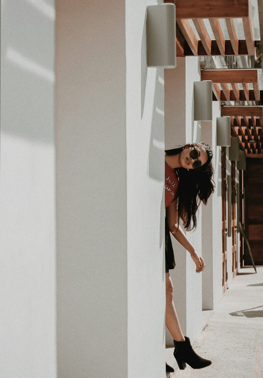 woman hiding behind white wall