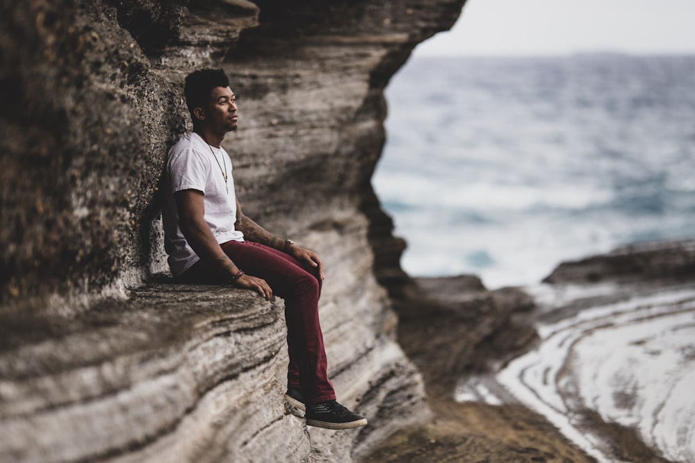 man sitting on rock formation during daytime