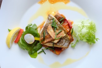 A beautifully plated trout dish garnished with fresh herbs and lemon slices.